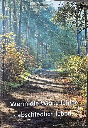 Ein Bild eines Pfades im herbstlichen Wald mit einer Aufschrift: „Wenn die Worte fehlen – abschiedlich leben“